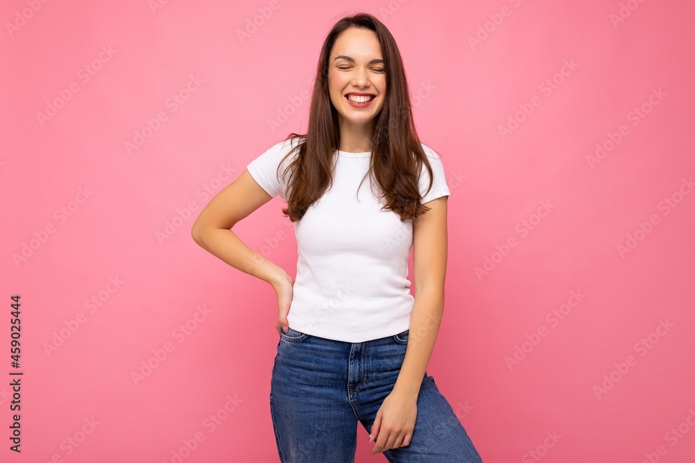Photo portrait of young beautiful smiling hipster brunette woman in white t-shirt with mockup. Sexy carefree female person posing isolated near pink wall with empty space in studio. Positive model Photo portrait of young beautiful smiling hipster brunette woman in white t-shirt with mockup. Sexy carefree female person posing isolated near pink wall with empty space in studio. Positive model