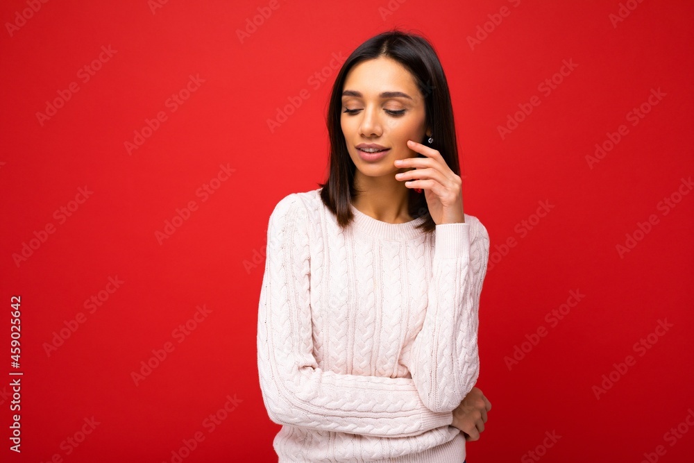 Charming cute nice adorable tender thoughtful young brunette woman in casual light knitted sweater isolated on red background with free space Charming cute nice adorable tender thoughtful young brunette woman in casual light knitted sweater isolated on red background with free space