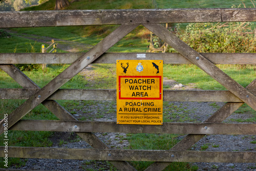 Poacher Watch Area sign in the British countryside.The sign is on a wooden gate.