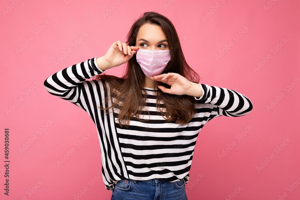 Shot of young attractive woman wearing mediacal face mask isolated over background wall. Protection against COVID-19 Shot of young attractive woman wearing mediacal face mask isolated over background wall. Protection against COVID-19