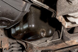 The exposed oil drain plug underneath the chassis of an SUV.