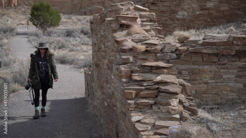 Young Female With a Photo Camera Walking by the Walls of Pueblo Remains, Chacoan Prehistoric Community Buildings, Chaco Culture National Historic Park, New Mexico USA photo