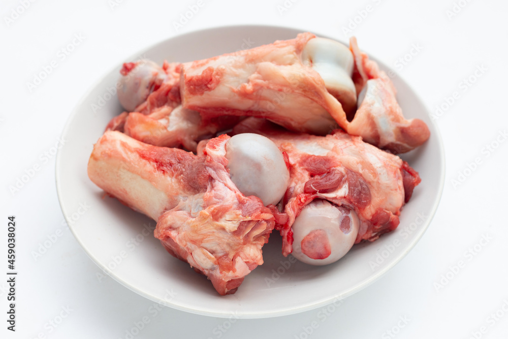 Raw pork bones in white plate on white background.