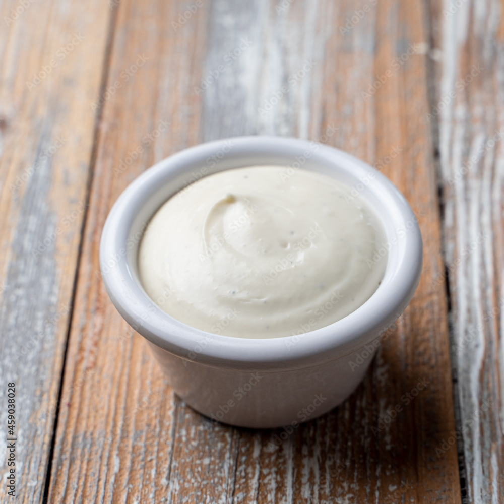 A single cup of mayonnaise on wooden background A single cup of mayonnaise on wooden background