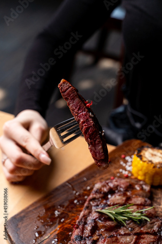 Female hands are cutting a thick juicy steak for commercial photo, close up, appetizing photo