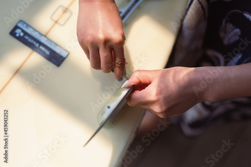 Girl plugging fiberglass fins in her surf board on surf club