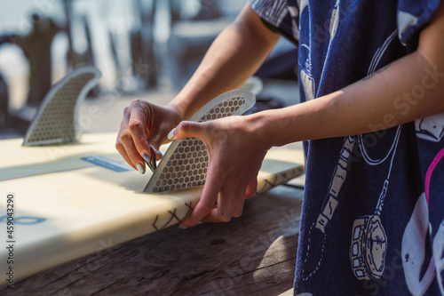 Girl plugging fiberglass fins in her surf board on surf club photo