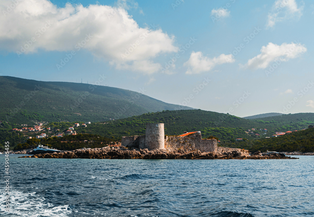 An island with the former Austrian fortress Arza. Mamula Island. In the background there is a mountain range, the Bay of Kotor, the Adriatic Sea. Close-up view from the sea from the yacht.