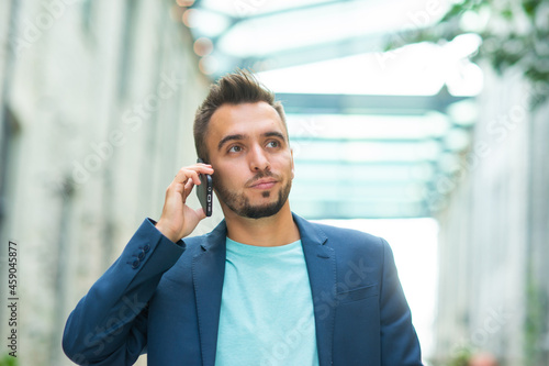 A young successful businessman is working outdoor using smartphone. Man in a casual wear. Business, freelance and remote work.