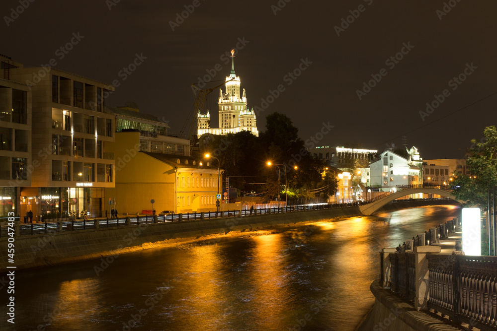 Fototapeta premium Moscow, Russia, Aug 25, 2021. Night view of Vodootvodny Canal embankment. Skyscraper building at Kotelnicheskaya embankment in background