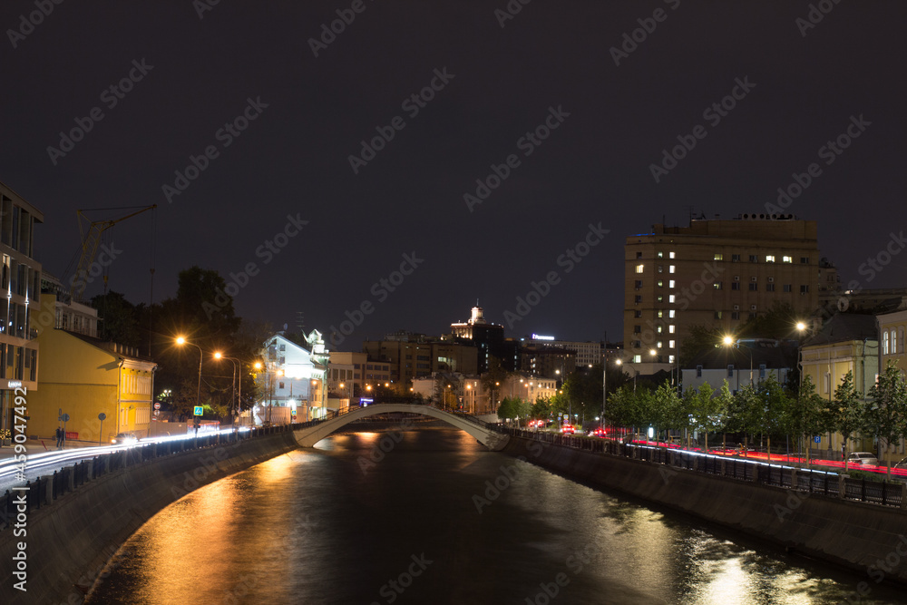 Moscow, Russia, Aug 25, 2021.  Night view of Vodootvodny Canal embankment.  Car traces. Pedestrian bridge