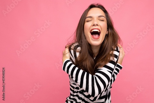 Photo shot of cute attractive pretty young delightful happy brunette woman wearing casual striped longsleeve isolated over colorful background with copy space