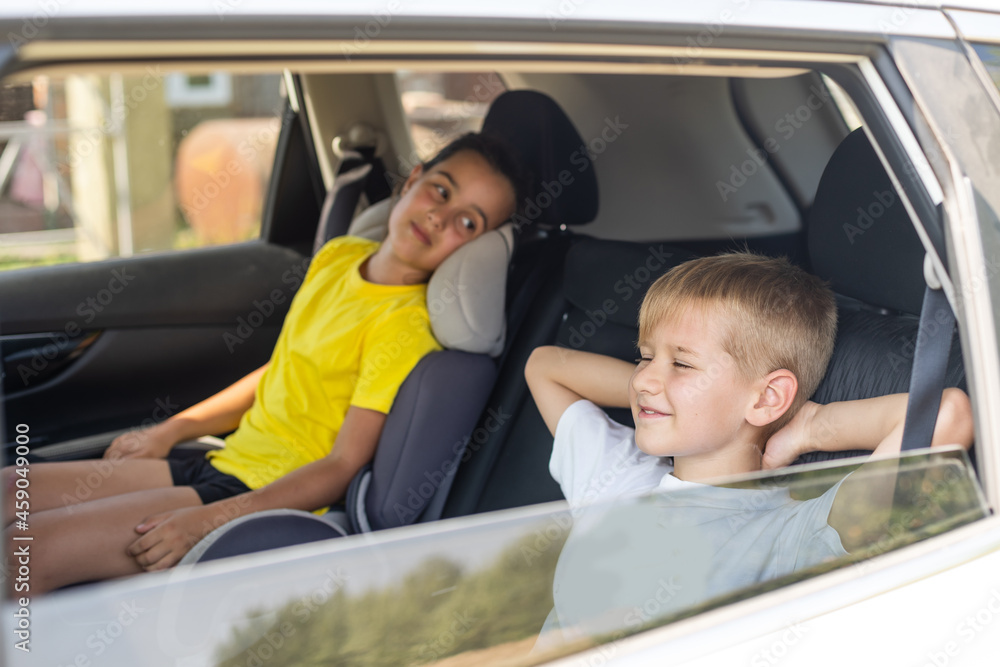 Happy kids, adorable toddler girl with teenager brother sitting together in modern car locked with safety belts enjoying family vacation trip on summer weekend