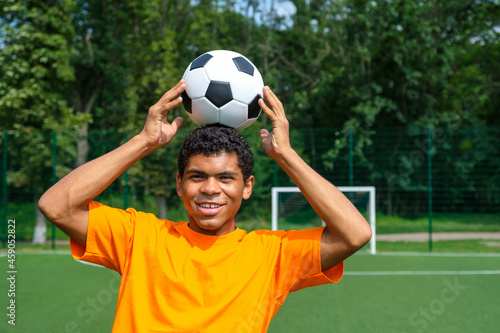 Brazilian soccer player trains and improves soccer ball control by juggling it on his head on sport ground in summer