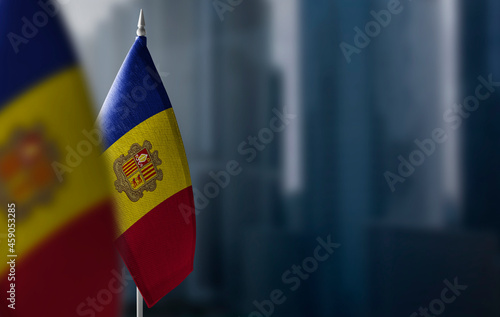 Small flags of Andorra on a blurry background of the city