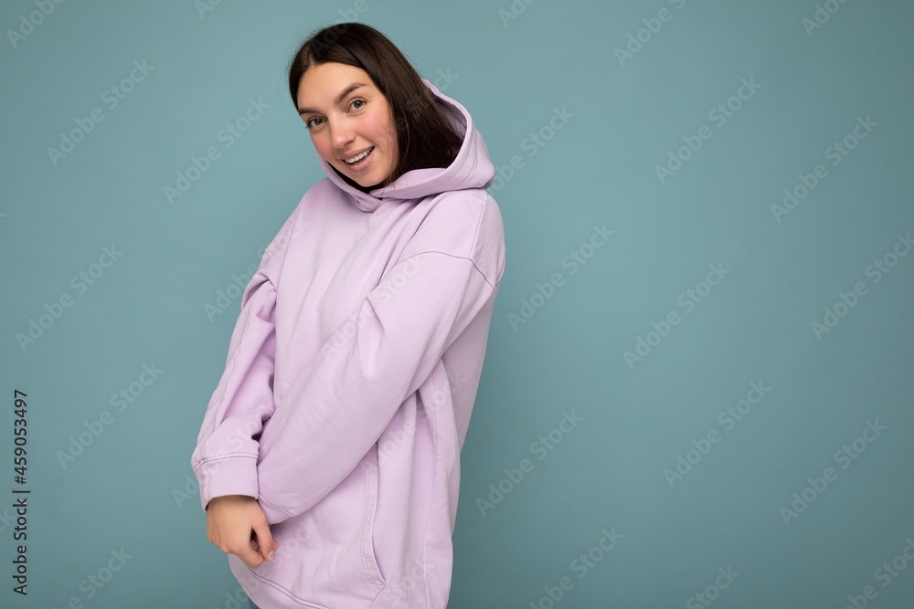 Fototapeta premium Young cute sttractive brunette woman with sincere emotions isolated on background wall with copy space wearing stylish purple hoodie. Happy cute concept