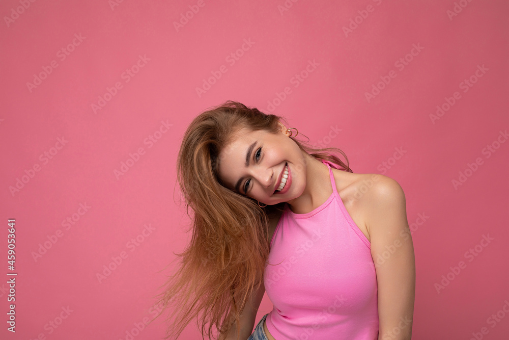 Photo shot of pretty joyful smiling young female person wearing casual trendy outfit standing isolated on colourful background with copy space looking at camera and having fun Photo shot of pretty joyful smiling young female person wearing casual trendy outfit standing isolated on colourful background with copy space looking at camera and having fun
