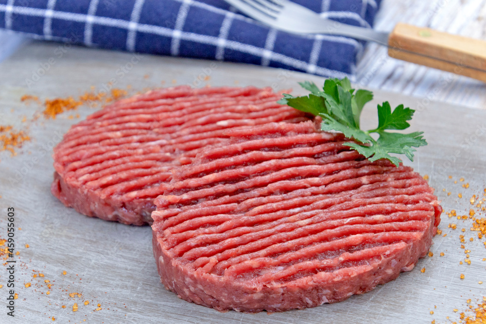 deux steaks hachés de boeuf crus sur une planche à découper deux steaks hachés de boeuf crus sur une planche à découper
