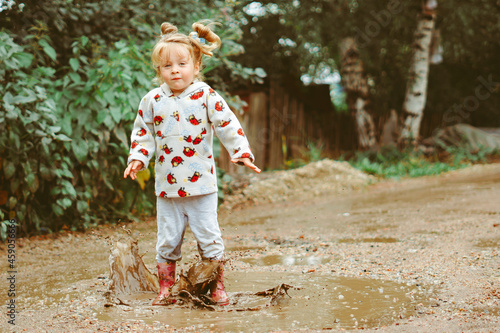 Fototapeta Naklejka Na Ścianę i Meble -  a child runs through puddles in rubber boots