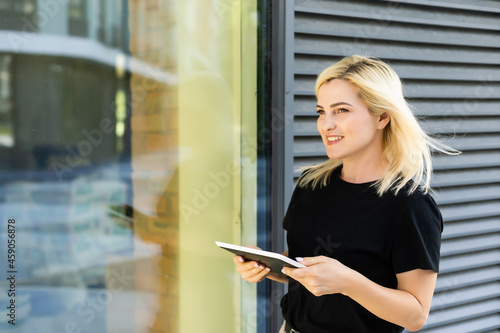 Portrait of a successful woman using digital tablet during quick break in front a corporate building.