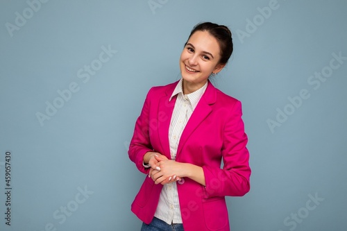 Photo portrait of young nice winsome beautiful positive smiling brunette woman with sincere emotions wearing casual white shirt and stylish pink jacket isolated over blue background with copy space