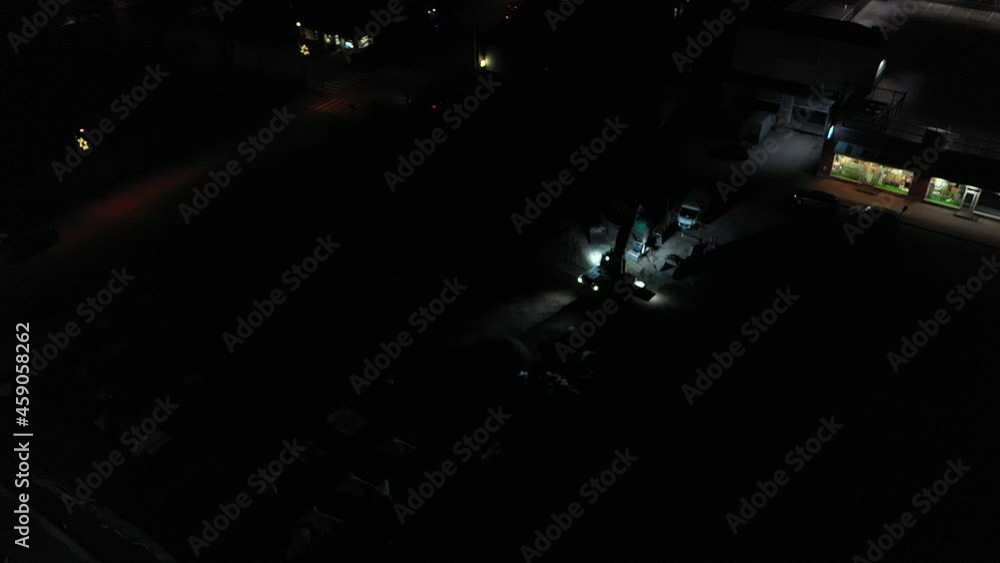 Aerial view of excavator demolishing a building, in middle of a dark city - circling, drone shot Aerial view of excavator demolishing a building, in middle of a dark city - circling, drone shot