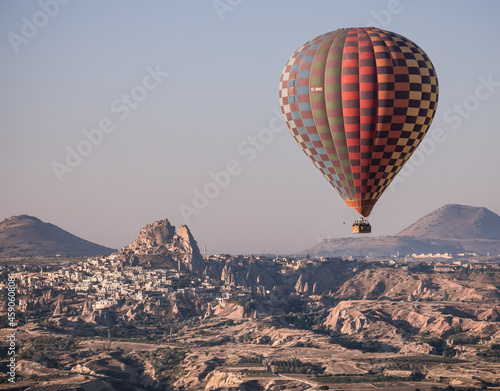colorful balloon in the flight in Cappadocia, in front of Uchisar rock houses