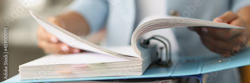 Woman examining information in folder with documents closeup photo