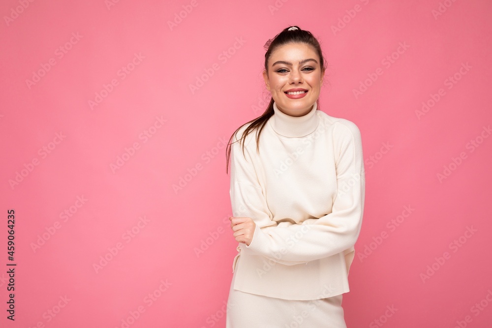 Obraz premium Lovely smiling young woman wearing warm sweater standing isolated over pink background, posing. Positive concept