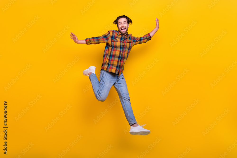 Full length photo of joyful brunet millennial guy run wear shirt jeans sneakers isolated on yellow background
