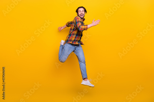 Full body photo of funny brunet young guy run wear shirt jeans sneakers isolated on yellow background