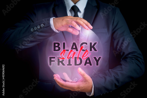 The man in the jacket suit, center between his hands has the words BLACK FRIDAY in black letters and SALES in red letters to remind you how prepared you are for the season. that is coming soon photo