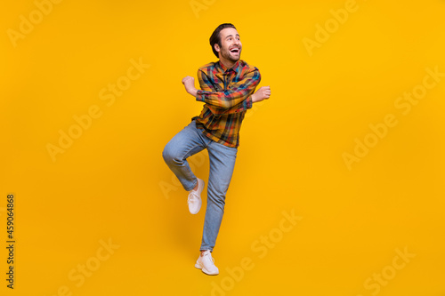 Full body photo of cute brunet young guy dance wear shirt jeans sneakers isolated on yellow background