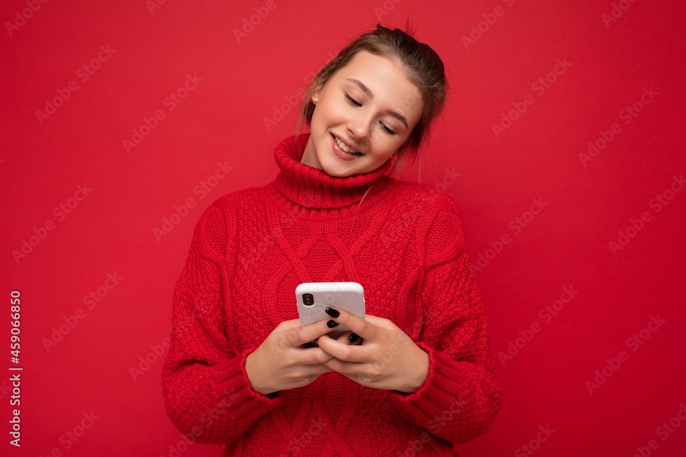 Photo shot of attractive positive good looking young woman wearing casual stylish outfit poising isolated on background with empty space holding in hand and using mobile phone messaging sms looking at Photo shot of attractive positive good looking young woman wearing casual stylish outfit poising isolated on background with empty space holding in hand and using mobile phone messaging sms looking at