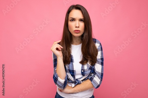 Shot of youngsad dissatisfied beautiful brunette woman with sincere emotions wearing trendy check shirt isolated on pink background with empty space and having doubts © Ivan Traimak