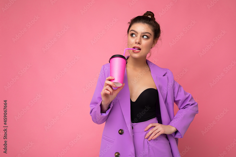 Charming young happy thinking brunette female person wearing stylish clothes isolated over colourful background wall holding paper cup for mockup drinking milkshake looking to the side and having an Charming young happy thinking brunette female person wearing stylish clothes isolated over colourful background wall holding paper cup for mockup drinking milkshake looking to the side and having an