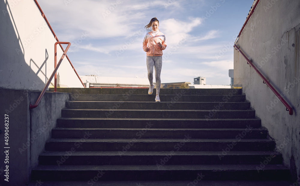 artistic symmetrical image of a caucasian female running down the stairs in sportswear