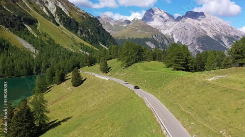 Aerial drone footage of a car driving on the Albula mountain pass road in the alps in Canton Graubunden in Switzerland. Shot with a forward following motion.  photo