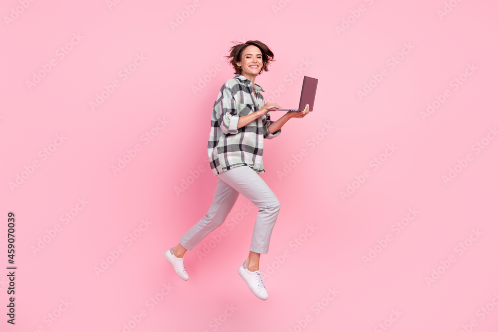 Full size profile side photo of young woman happy positive smile go walk jump online laptop isolated over pink color background