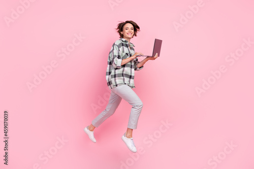 Full size profile side photo of young woman happy positive smile go walk jump online laptop isolated over pink color background