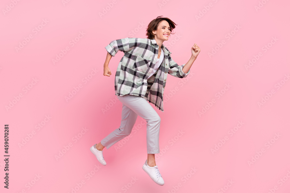 Full body profile side photo of young woman happy positive smile jump go walk run fast isolated over pink color background Full body profile side photo of young woman happy positive smile jump go walk run fast isolated over pink color background