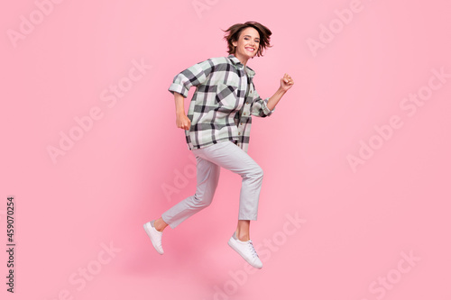 Full size profile photo of cute millennial brunette lady run wear shirt trousers isolated on pink background