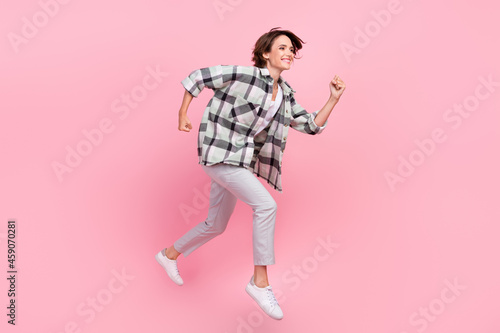 Full body profile side photo of young woman happy positive smile jump go walk run fast isolated over pink color background