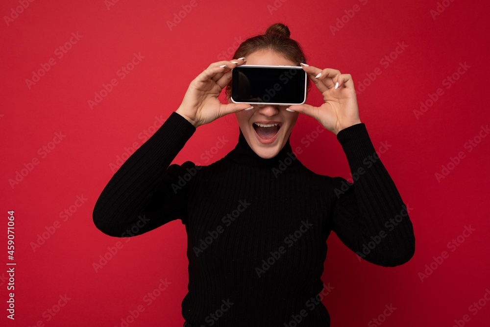 Photo of beautiful smiling young woman good looking wearing casual stylish outfit standing isolated on background with copy space holding smartphone showing phone in hand with empty screen display for Photo of beautiful smiling young woman good looking wearing casual stylish outfit standing isolated on background with copy space holding smartphone showing phone in hand with empty screen display for