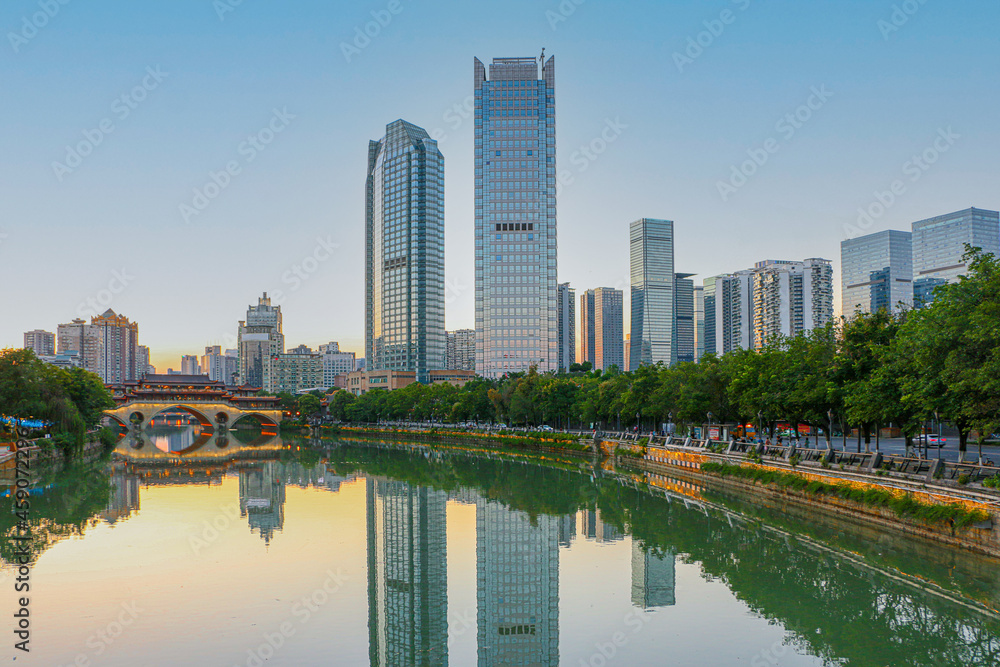 Sunset over the iconic Anshun Bridge in Chengdu, Sichuan, lit up ready for the evening, with modern skyscrapers on the right, overlooking the Jinjiang River with reflections