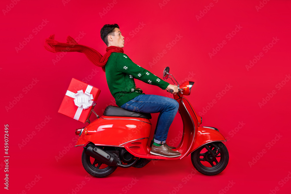 Full length body size photo crazy guy sitting on bike in scarf driving scooter isolated vibrant red color background Full length body size photo crazy guy sitting on bike in scarf driving scooter isolated vibrant red color background