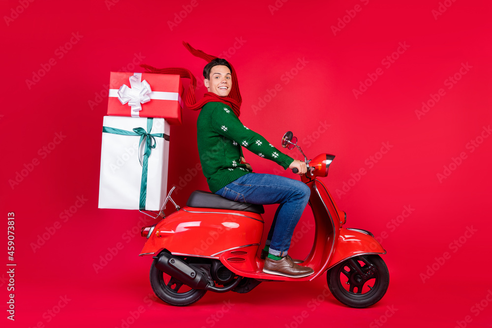 Full length body size photo man guy sitting on bike wearing scarf delivering gift isolated vibrant red color background Full length body size photo man guy sitting on bike wearing scarf delivering gift isolated vibrant red color background