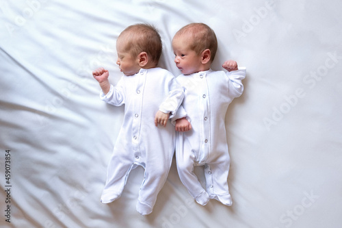 Konstfotografi Newborn twins on the bed, in the arms of their parents, on a white background