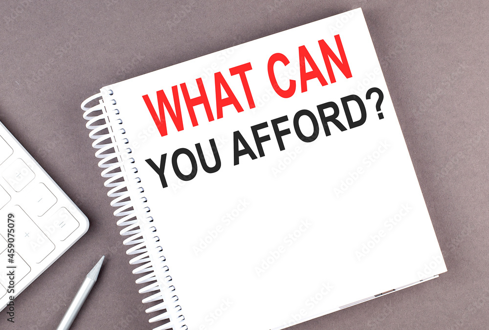 WHAT CAN YOU AFFORD text on notebook with calculator and pen,business WHAT CAN YOU AFFORD text on notebook with calculator and pen,business