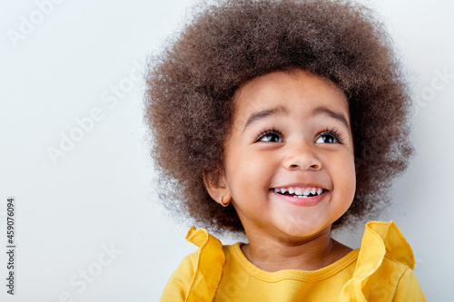 Surprised little afro black girl isolated on white studio background, having fun, copyspace for ad. Looks happy, cheerful, sincere. Childhood, education, human emotions, facial expression concept.